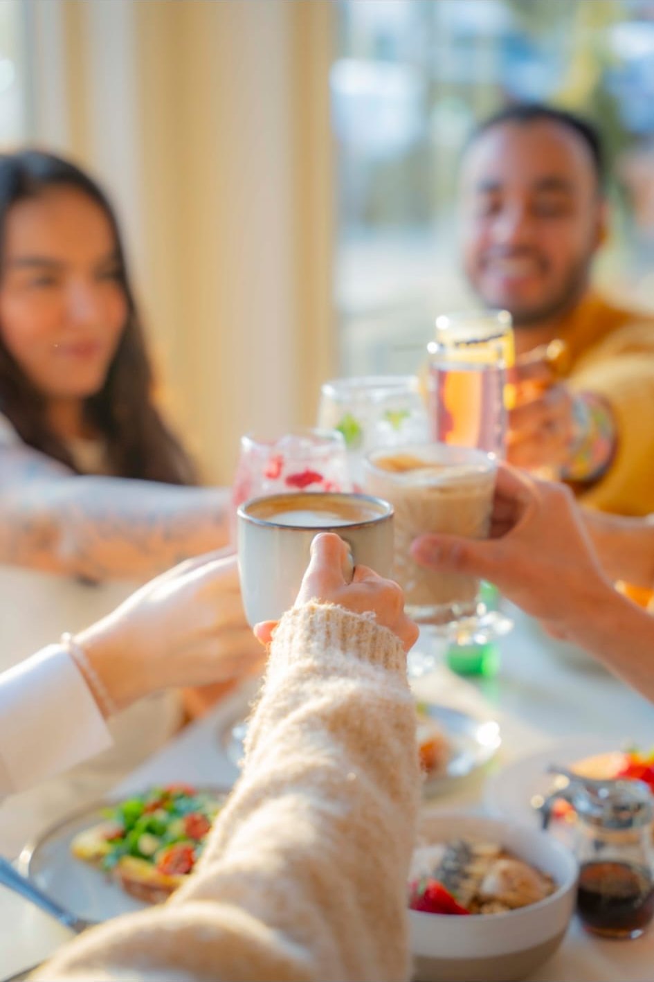 Friends mid-toast with mimosas, bright weekend light, laughter in motion.
